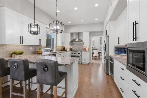 a kitchen with granite countertop a table chairs stove and cabinets