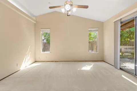an empty room with windows and chandelier fan