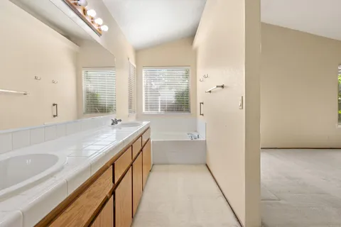 a bathroom with a granite countertop sink a large mirror and a bathtub