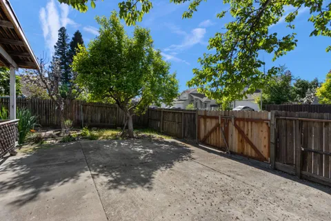a view of backyard with wooden fence and trees