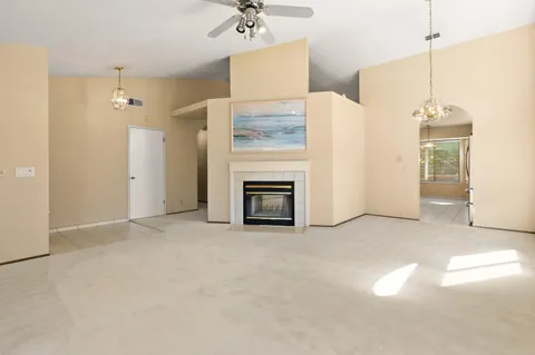 an empty room with a fireplace and chandelier fan