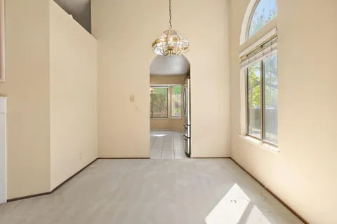 a view of an empty room with window and chandelier fan
