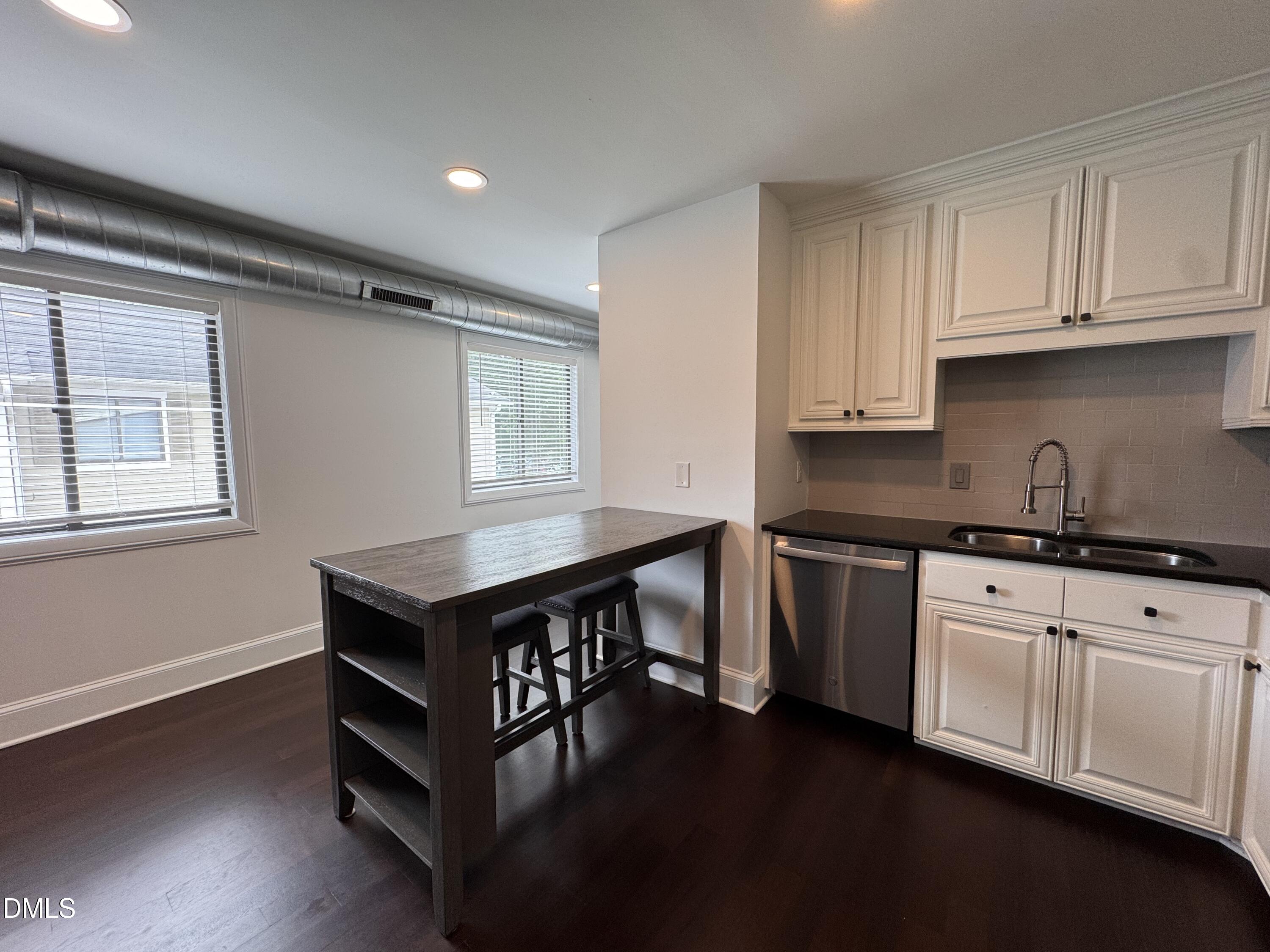2204 Stafford Avenue, Unit 202 Raleigh, NC 27607 - Photo 5 of 15 a kitchen with granite countertop a stove a sink and white cabinets with wooden floor