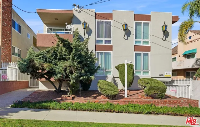 a front view of a multi story residential apartment building with yard and parking space