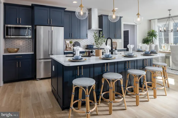 a kitchen with stainless steel appliances a dining table chairs refrigerator and sink