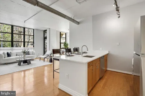 a kitchen with stainless steel appliances kitchen island granite countertop a dining table chairs and a refrigerator