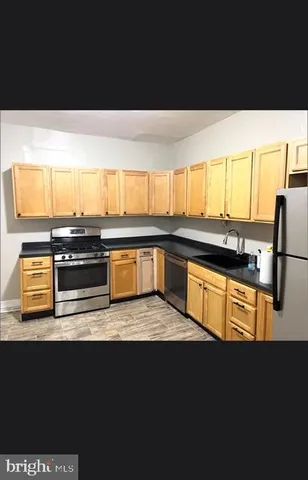 a kitchen with stainless steel appliances a sink dishwasher and a black refrigerator with wooden floor