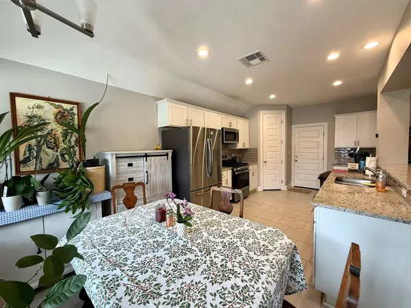 a large kitchen with sink a refrigerator and chairs