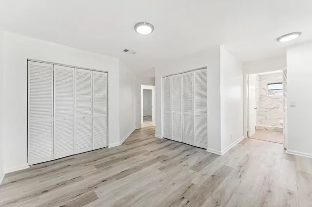 an empty room with wooden floor & closet area