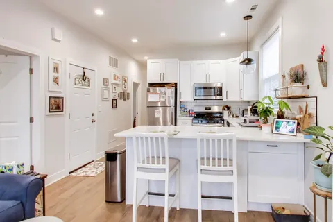 a kitchen with stainless steel appliances white cabinets and wooden floor