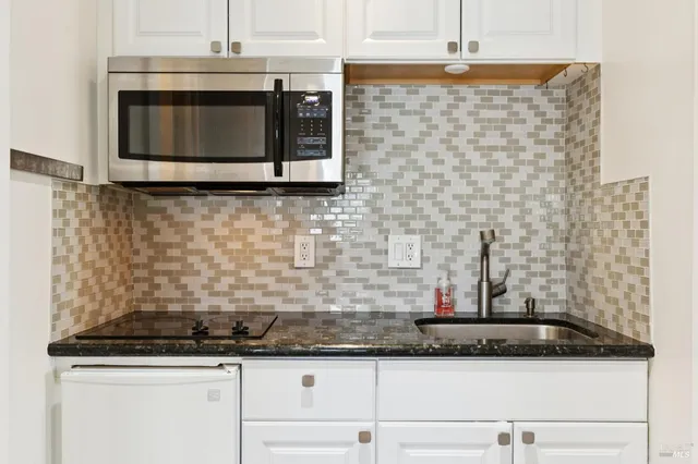 a kitchen with granite countertop white cabinets and stainless steel appliances