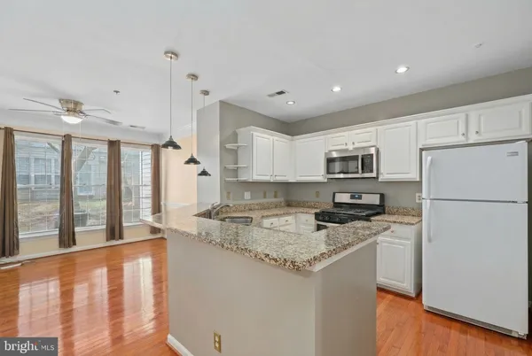 a kitchen with stainless steel appliances granite countertop a refrigerator a stove top oven a sink and a refrigerator