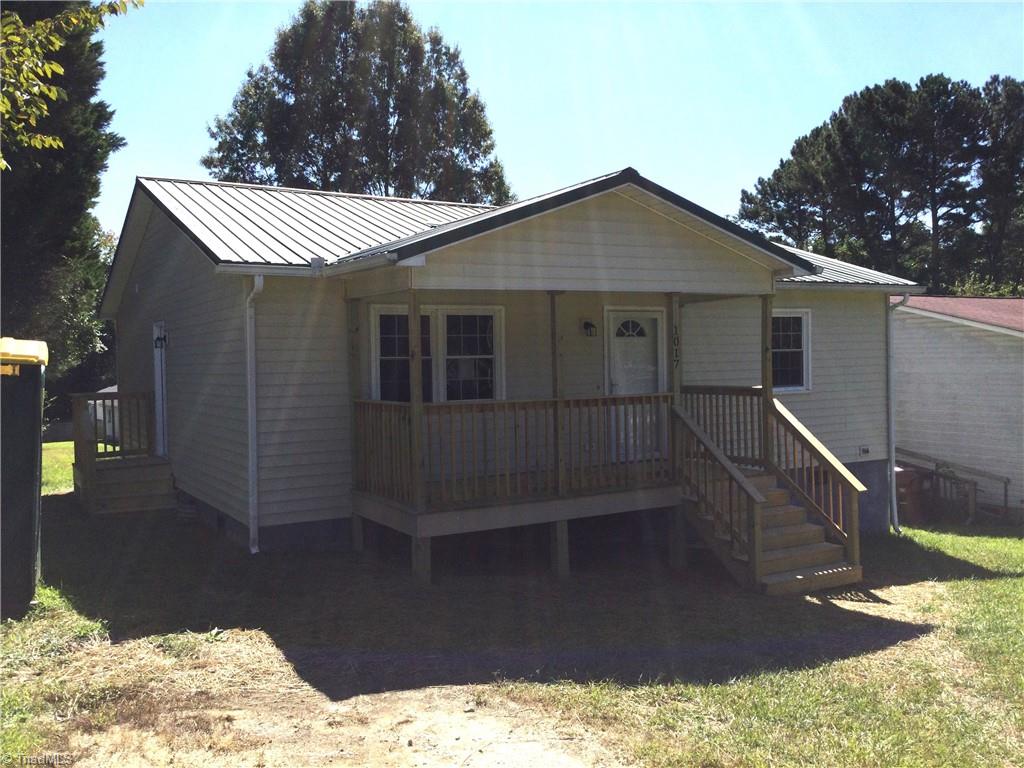 1017 Sales Street High Point, NC 27260 - Photo 11 of 40 Left Front View: Here we can see the covered front porch, the green grass and mature trees in the backyard and the gravel driveway to the left side. You have a side door entry and deck conveniently located near the driveway. Picture yourself relaxing on the covered front porch, drinking a cool beverage. Life is GOOD. Side door opens into the kitchen area.