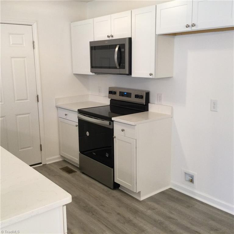 1017 Sales Street High Point, NC 27260 - Photo 17 of 40 Kitchen: Features include vinyl plank flooring for easy cleaning, fresh new paint, bright cabinets with new fixtures. Appliance include SST dishwasher, attached microwave and a stove. The side entry door opens to the deck and driveway area.