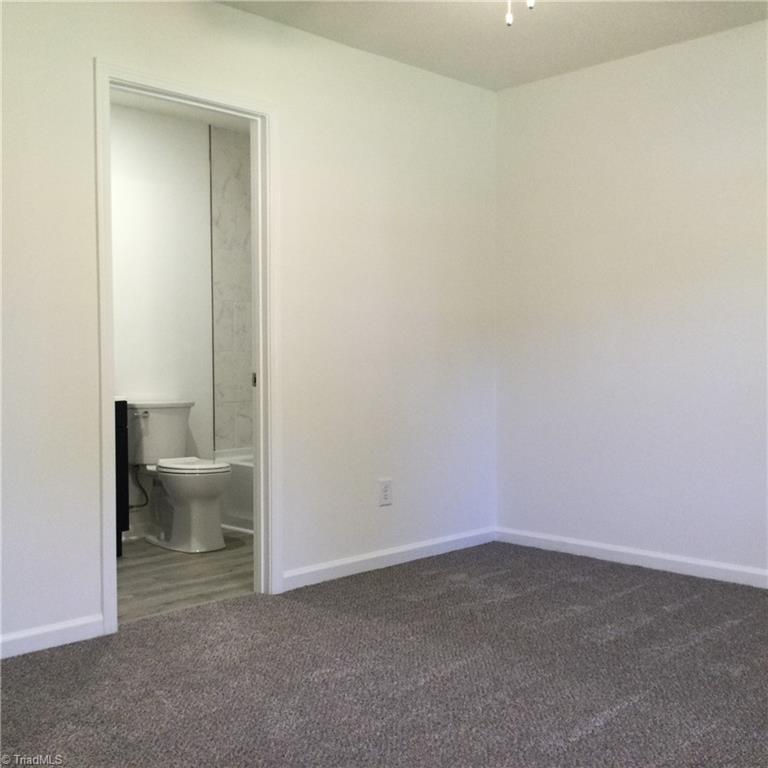 1017 Sales Street High Point, NC 27260 - Photo 22 of 40 Primary Bedroom: Features include carpet flooring to help keep you warm on cool mornings, a window for natural lighting, fresh new paint and a ceiling fan with light. The open door on the left is to the En-Suite bathroom and WIC.