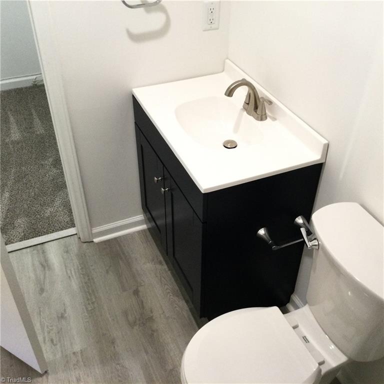 1017 Sales Street High Point, NC 27260 - Photo 23 of 40 Primary En-Suite Bathroom: Features include vinyl plank flooring for easy cleaning, fresh new paint and a decorative vanity with new fixtures. You also have the tub/shower unit with decorative wall covering. The the left side is the WIC closet with carpet flooring, lighting and storage shelves.