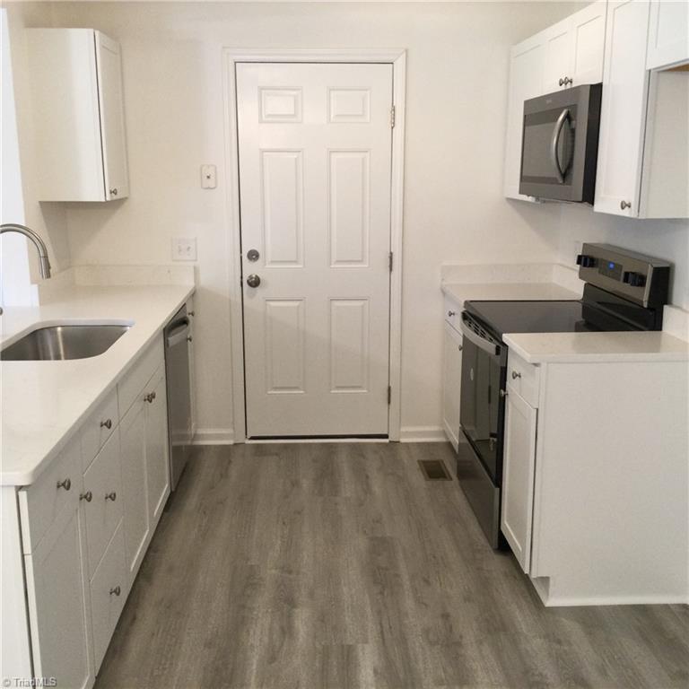 Kitchen: Features include vinyl plank flooring for easy cleaning, fresh new paint, bright cabinets with new fixtures. Appliance include SST dishwasher, attached microwave and a stove. The closed door opens to the side entry, deck with access to the driveway.