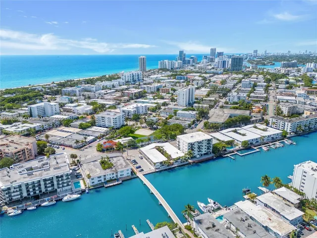 an aerial view of a city with lots of residential buildings ocean and mountain view in back