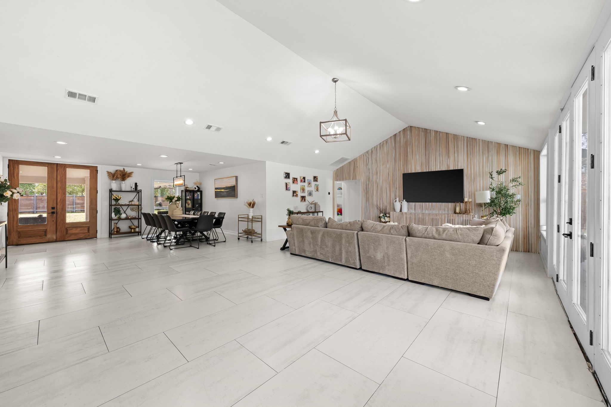 8800 Brae Acres Road Houston, TX 77074 - Photo 13 of 48 The family room has a vaulted ceiling that rises to a peak at the center — giving this space considerably more volume than the footprint alone would suggest. Large-format tile connects it continuously to the kitchen and dining area, and French doors along the rear wall open directly to the covered patio and pool.