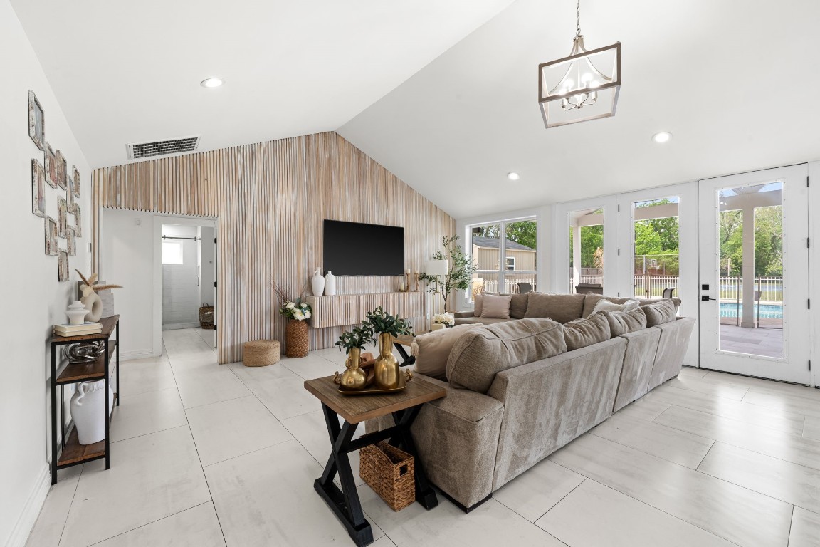 8800 Brae Acres Road Houston, TX 77074 - Photo 14 of 48 A full-height wood-slat accent wall anchors the room while abundant natural light floods through the bay of windows and French doors opening to the expansive outdoor space.