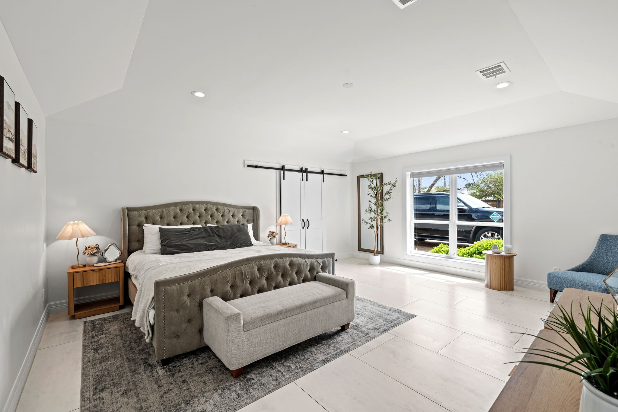 8800 Brae Acres Road Houston, TX 77074 - Photo 21 of 48 This stunning primary bedroom is filled with natural light and lofty vaulted ceilings add volume to a room with enough footprint for a dedicated sleeping area and a separate sitting area. Sliding barn doors open to the expansive walk-in closet and spa-like bath beyond.