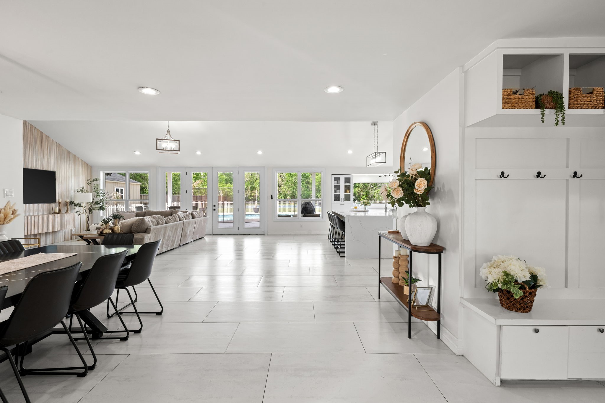 8800 Brae Acres Road Houston, TX 77074 - Photo 4 of 48 Step through the front doors and the full depth of the home opens up — large-format light gray tile runs from the entry threshold all the way to the French doors at the rear elevation, a sightline that immediately communicates the scale. To the right, a built-in drop zone with built-in white cabinetry, coat hooks, and bench keep everyday arrivals organized without sacrificing a separate room.