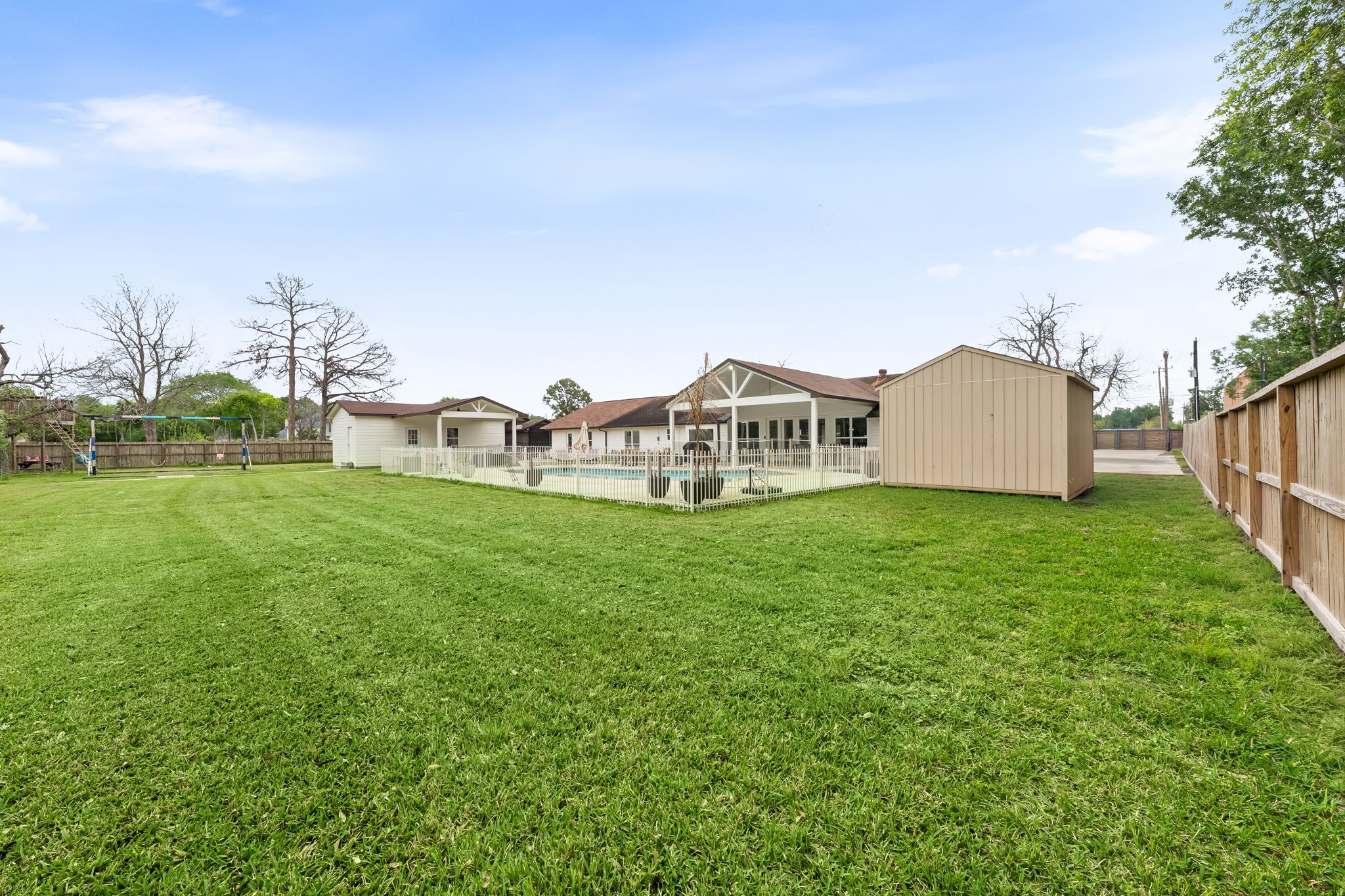 8800 Brae Acres Road Houston, TX 77074 - Photo 40 of 48 From the rear boundary, the lot's depth becomes the point — a broad open lawn extends from the back fence all the way to the storage shed, pool enclosure, and covered patio, with the main house at the far end. This is what 1.246 acres actually looks like from the inside.
