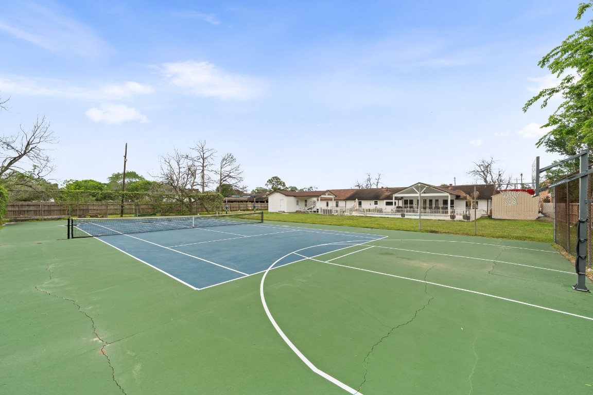 8800 Brae Acres Road Houston, TX 77074 - Photo 43 of 48 From the baseline, the court's full length opens up — net centered, the opposite end backed by a mature tree line, the whole court tucked into the rear of the lot behind its own perimeter fence. Private, maintained, and genuinely on-property — not a shared amenity, not a short walk away.