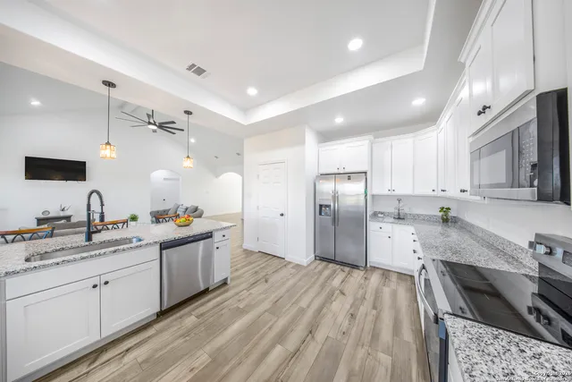 a large kitchen with stainless steel appliances kitchen island granite countertop a sink stove and refrigerator