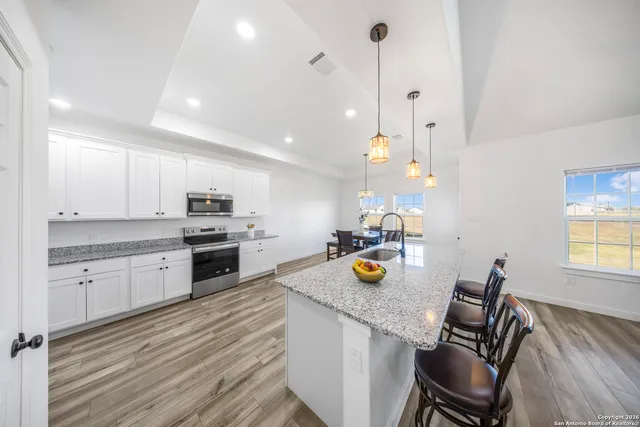 a kitchen with a sink a stove and chairs with wooden floor