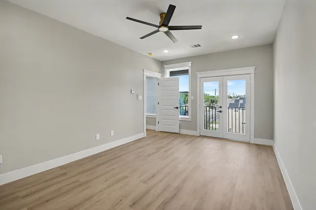 a view of an empty room with a window and wooden floor