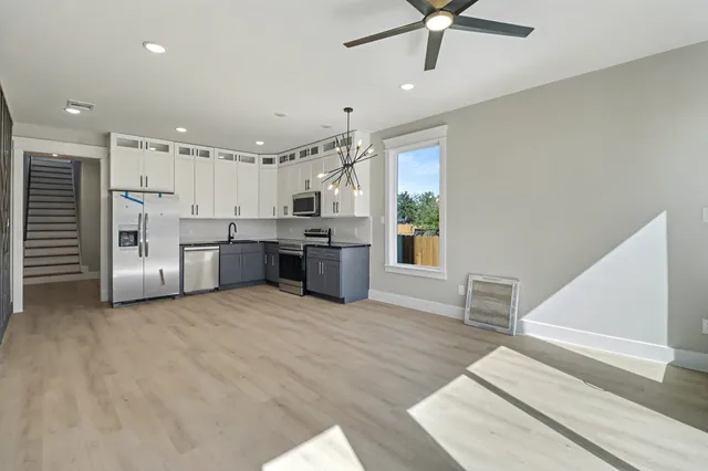 a large white kitchen with stainless steel appliances kitchen island granite countertop a refrigerator and a stove top oven