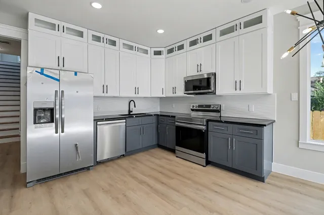 a kitchen with granite countertop a refrigerator and a stove top oven