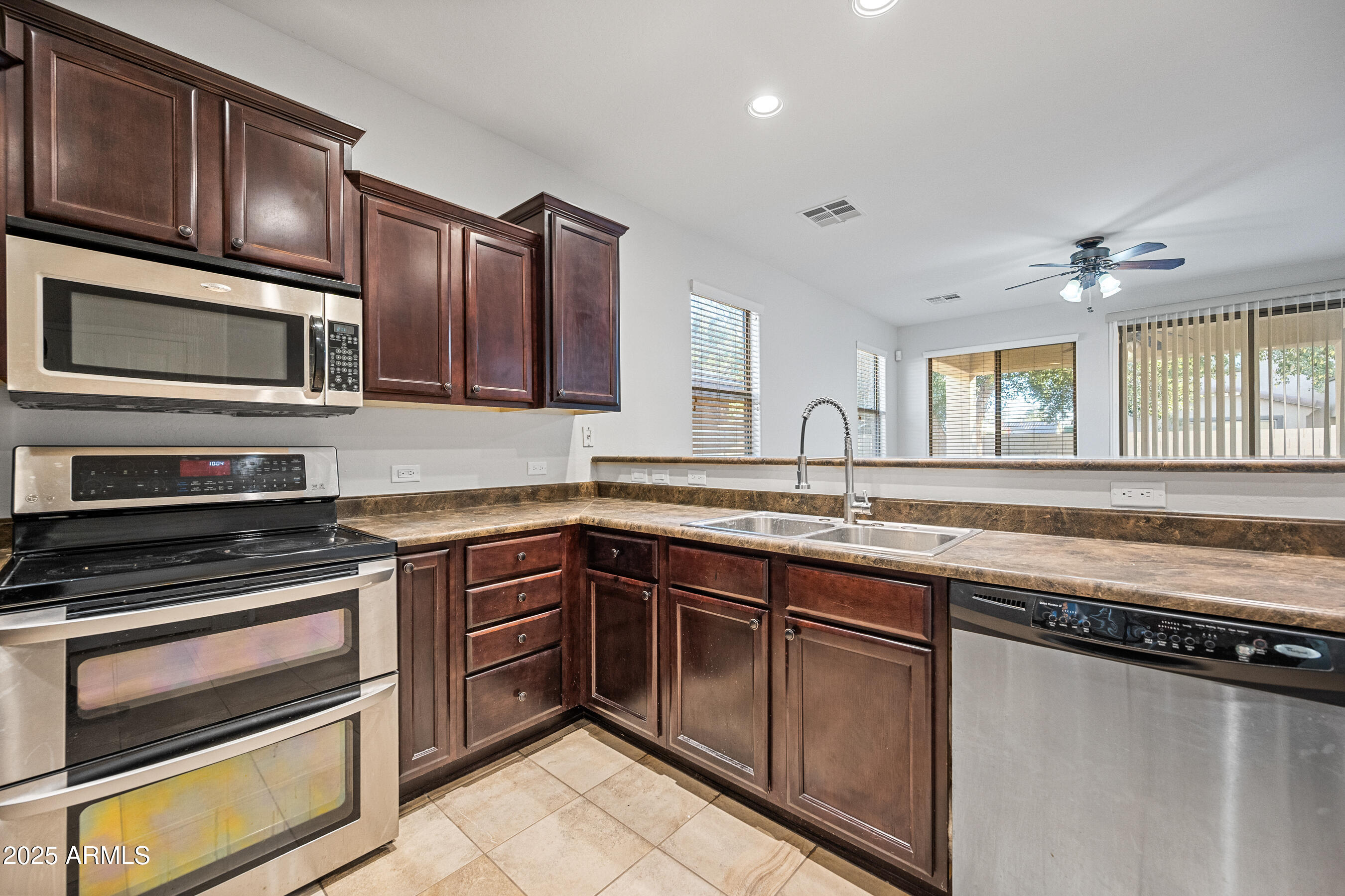 10805 West Woodland Avenue Avondale, AZ 85323 - Photo 11 of 25 a kitchen with stainless steel appliances granite countertop a stove microwave and cabinets