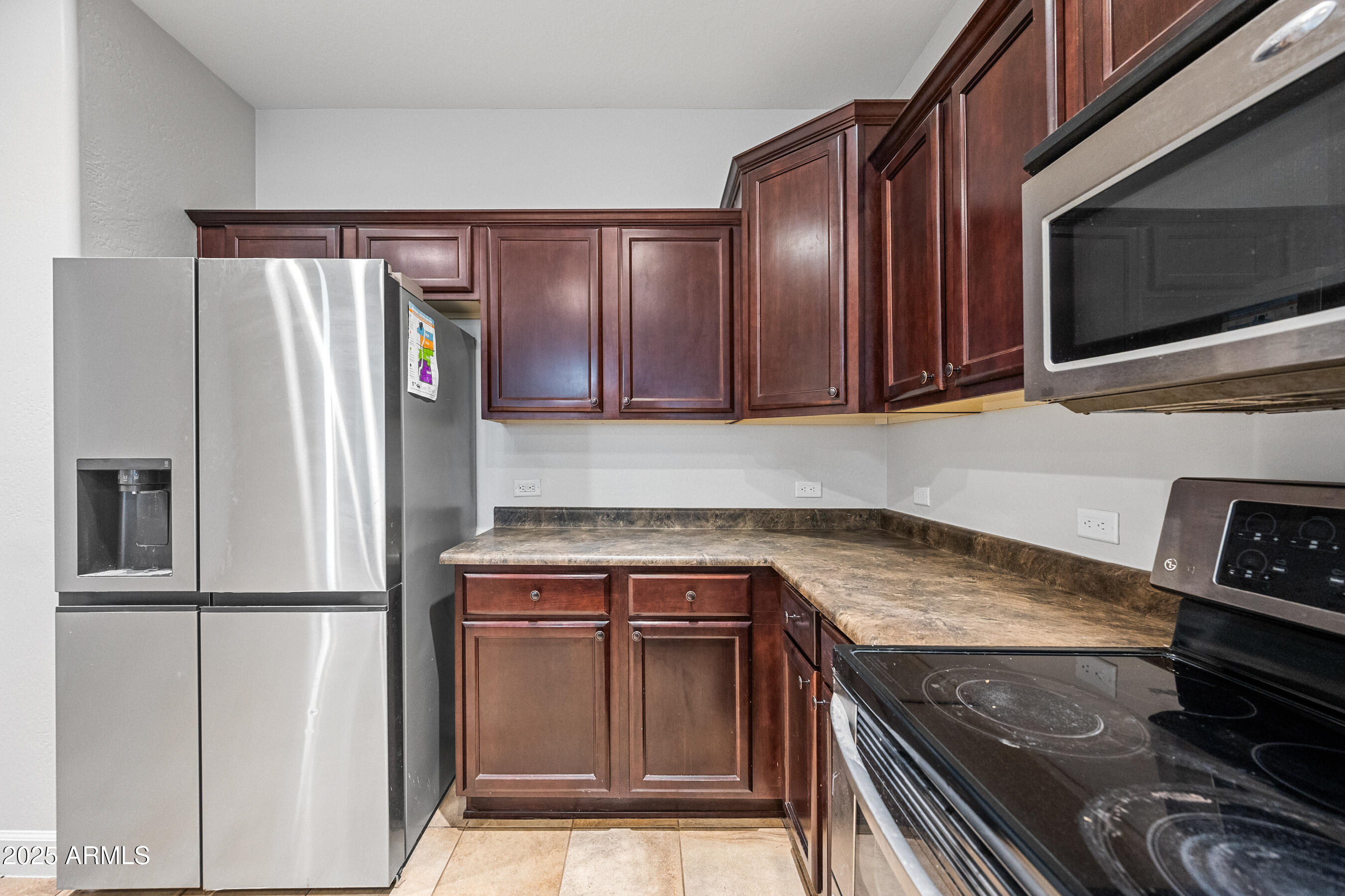 10805 West Woodland Avenue Avondale, AZ 85323 - Photo 12 of 25 a kitchen with stainless steel appliances granite countertop a refrigerator stove and microwave
