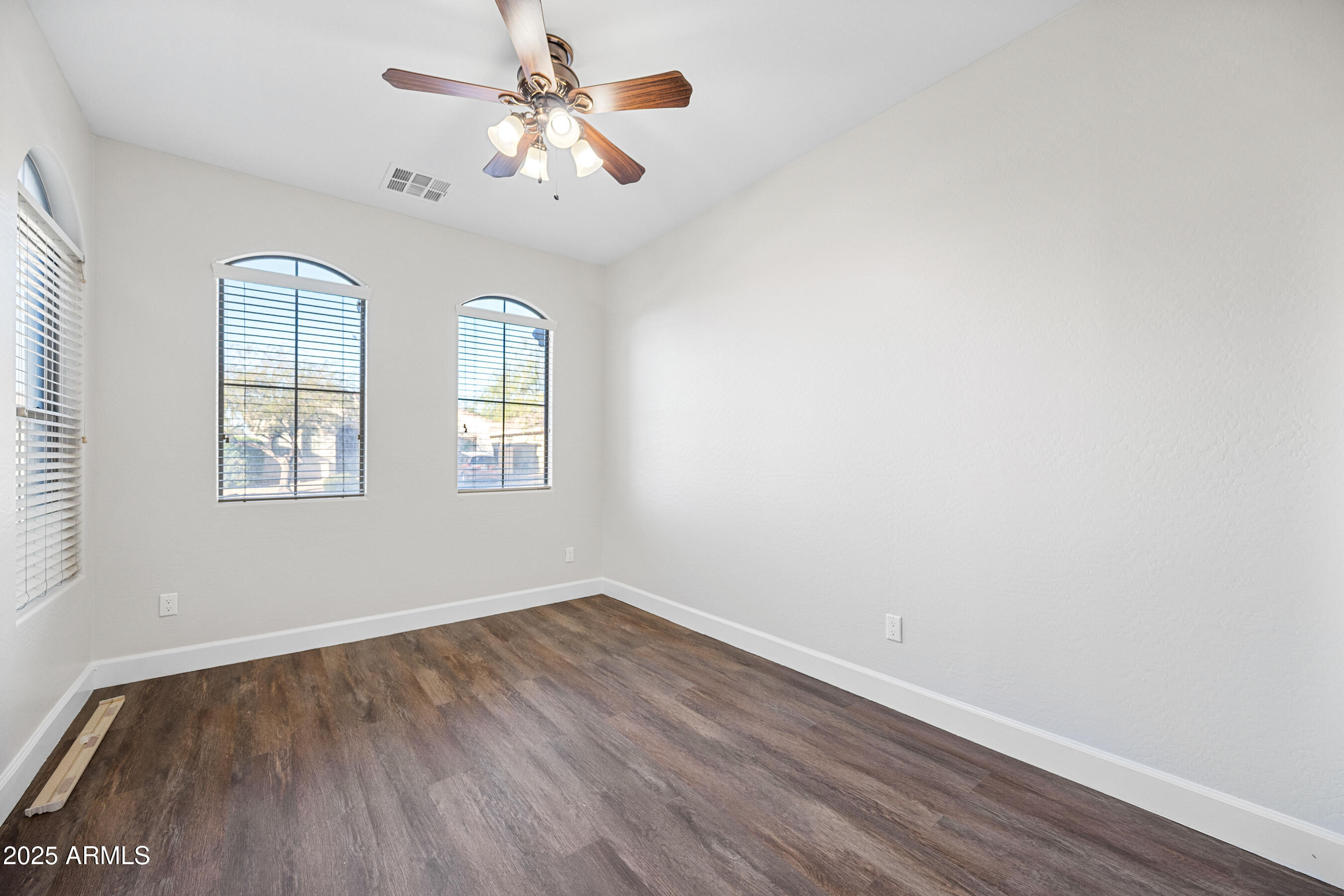 10805 West Woodland Avenue Avondale, AZ 85323 - Photo 20 of 25 an empty room with wooden floor chandelier fan and windows