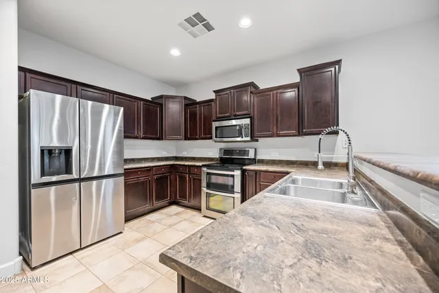 a kitchen with granite countertop a refrigerator and a stove top oven