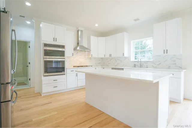 a kitchen with kitchen island white cabinets and stainless steel appliances