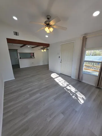 a view of an empty room with wooden floor and a window