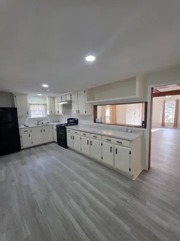 a large kitchen with a lot of counter space and wooden floor