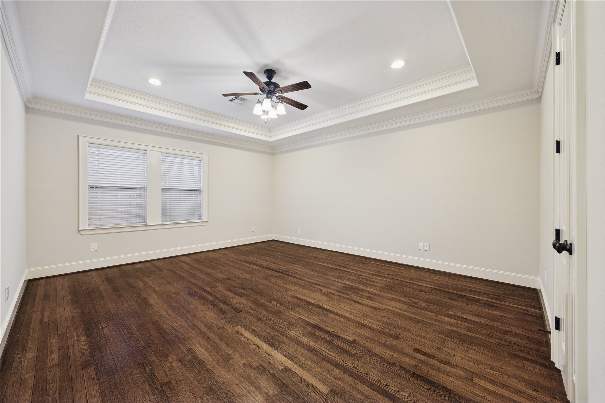 840 Alexander Street Houston, TX 77007 - Photo 18 of 39 This spacious primary suite features rich hardwood floors, a tray ceiling with recessed lighting, and a ceiling fan. Large covered window allows ample natural light, creating a bright yet private retreat.