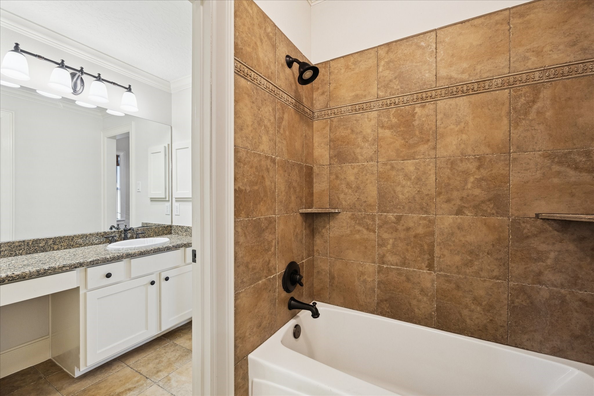 840 Alexander Street Houston, TX 77007 - Photo 23 of 39 This shared bathing room features a tiled shower with built-in shelves and a bathtub. The vanity area includes a granite countertop with a sink, white cabinetry, and modern light fixtures, offering a clean and functional shared space.