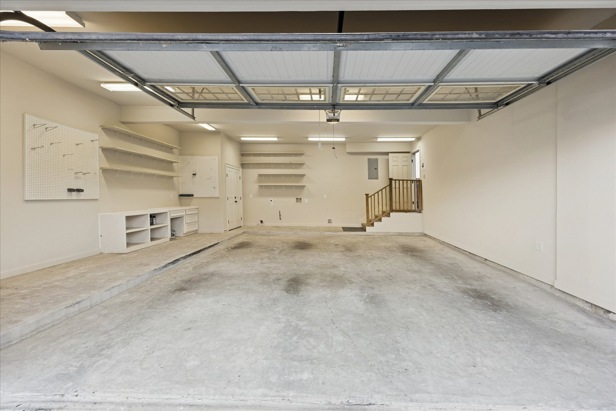 840 Alexander Street Houston, TX 77007 - Photo 29 of 39 This spacious 2 car extra large garage offers ample room for vehicles and storage, featuring built-in shelving, a workbench, and a pegboard for organizing tools. The clean, well-lit space includes easy access to the home through a small staircase at the breezeway. Additionally, the storage closet pictured on the left side of the photo is air conditioned for optimal storage capabilities.
