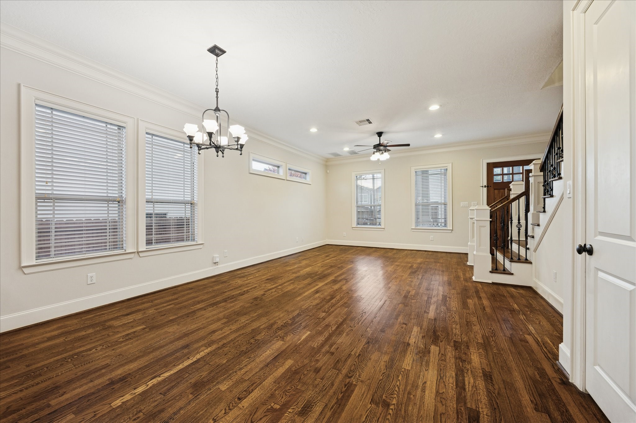 840 Alexander Street Houston, TX 77007 - Photo 10 of 39 This spacious, open-concept living area with hardwood floors, ample natural light from multiple windows, and elegant fixtures including a ceiling fan and chandelier. This space can be used as a formal entry, living and dining room. The staircase leading upstairs to all bedrooms, including the primary suite.
