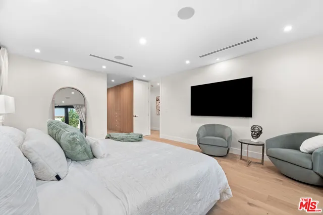 a bedroom with a bed a couch and a flat screen tv