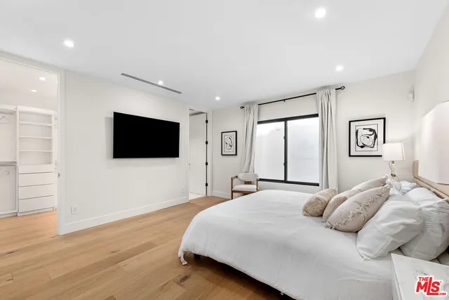 a spacious bedroom with a bed and a flat screen tv