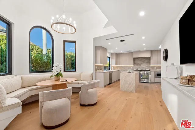 a living room with furniture kitchen view and a large window