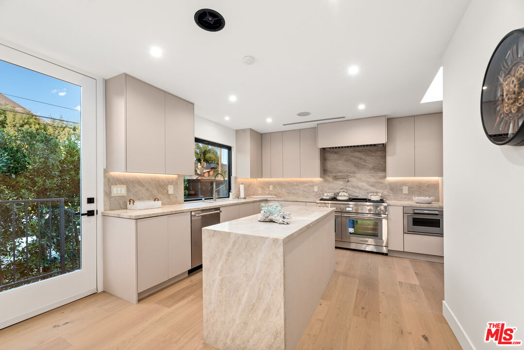 100 South La Jolla Avenue Los Angeles, CA 90048 - Photo 10 of 31 a kitchen with stainless steel appliances a stove a sink a refrigerator white cabinets and wooden floor