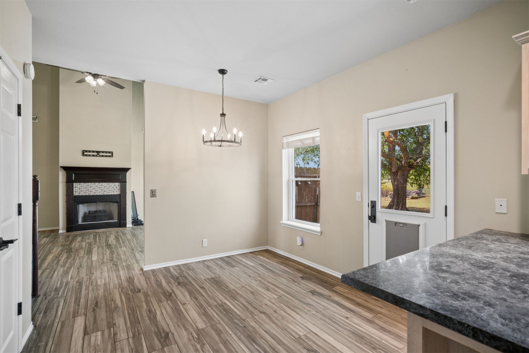 175 Alt 75 Mounds, OK 74047 - Photo 22 of 41 Wood-finish flooring throughout, a modern chandelier, and a dark wood-mantled fireplace with a tiled surround