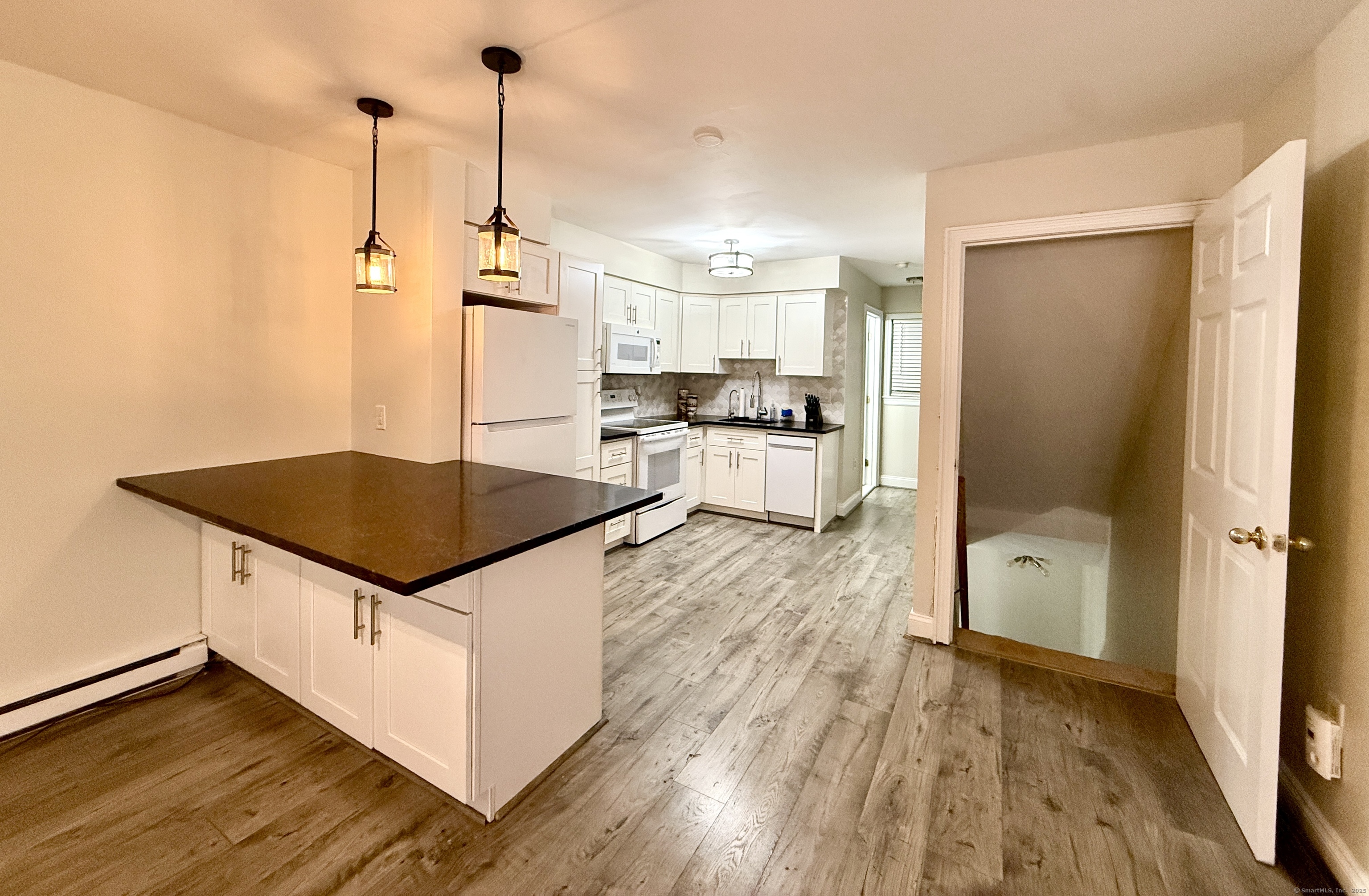 133 Main Street, Unit 5 Norwalk, CT 06851 - Photo 1 of 1 a kitchen with kitchen island a counter top space a sink a wooden floor and a window